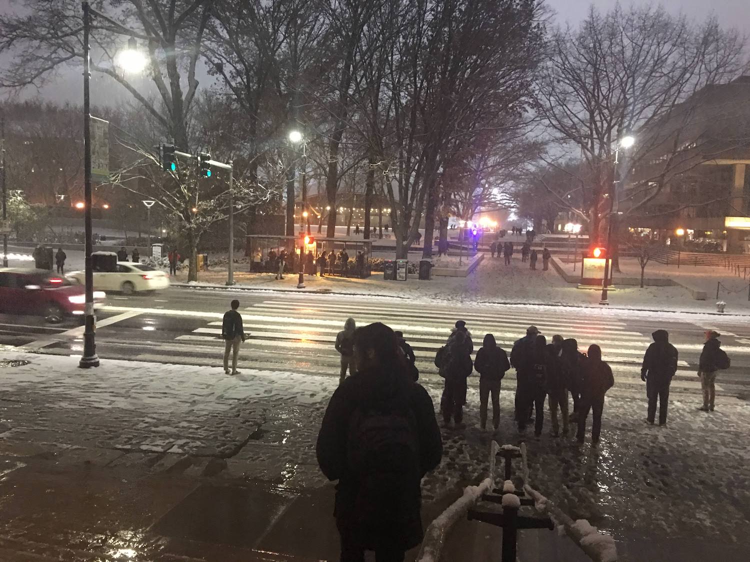 Walking down the steps of the MIT dome in the snow. The street lamps reflect off the wet streets and students head home during finals.